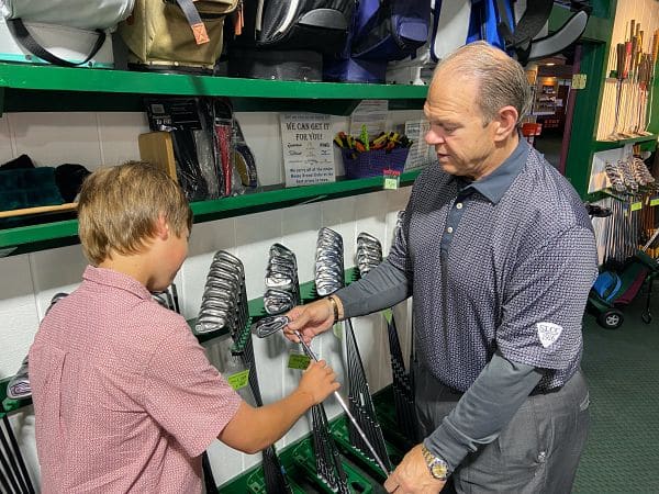 this is a picture of the owner showing golf clubs to a customer